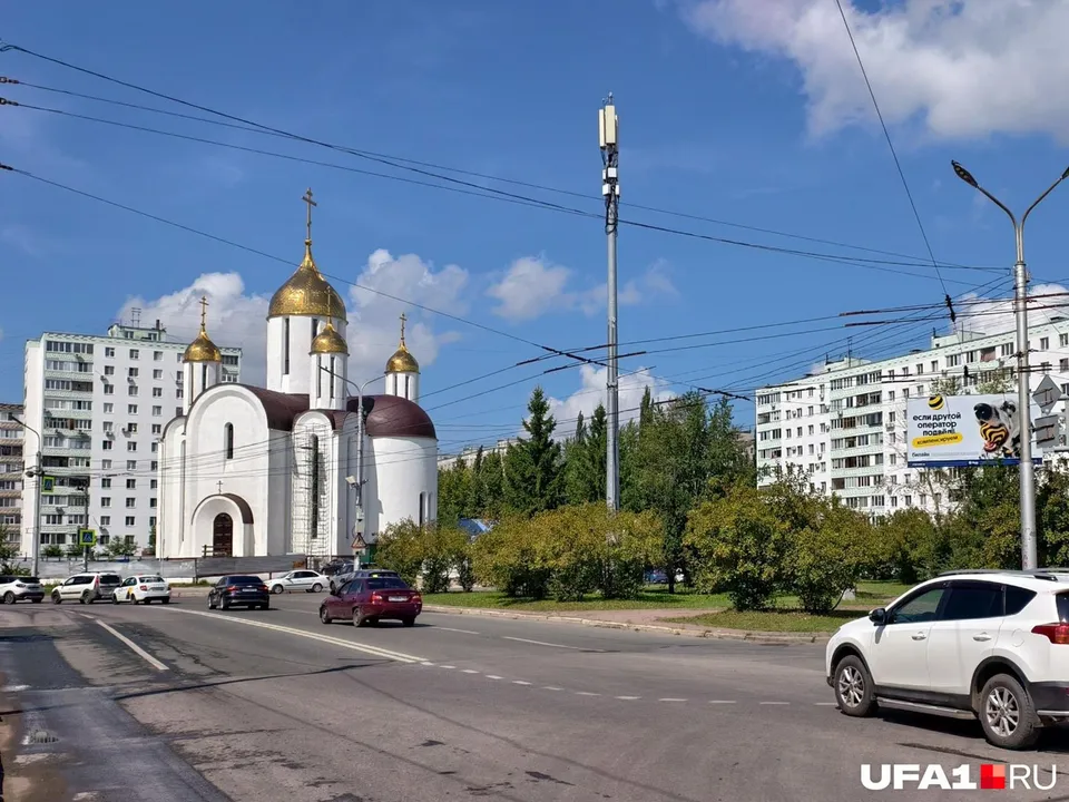 Белый пятиглавый храм с золотыми и чёрными куполами на фоне жилых высоток микрорайона Сипайлово
